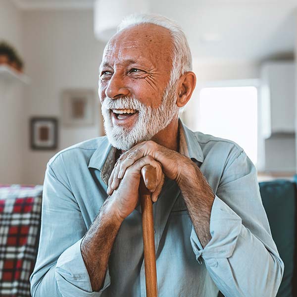 Happy senior man sitting and holding his walking stick